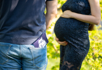 Junger, legere gekleideter Mann in Jeans und T-Shirt hat ein Ultrashallbild seines ungeborenen...