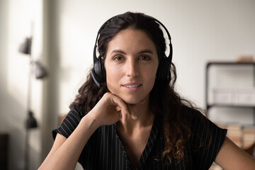 Call center worker. Headshot portrait of pleasant millennial hispanic woman in wireless headphone...