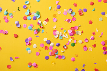 Colorful confetti on yellow background.Copy space