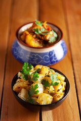 Close-up of Indian vegetarian classic combination of dishes  Jeera Aloo (Potatoes in cumin Flavored ) and spicy Potato and Tomato curry garnished with green coriander fresh leaves.