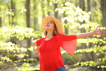 Excited woman spreading in a green forest a sunny day