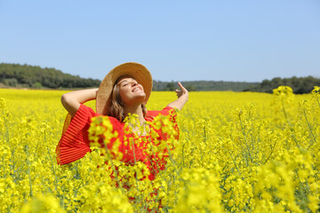 Excited woman in red spreading in a yellow field