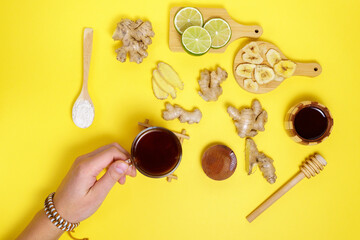 Tea with ginger lime, honey dried fruits on a yellow background. top view