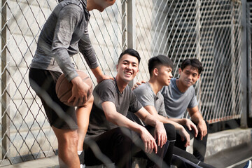 asian young adults resting relaxing on outdoor basketball court