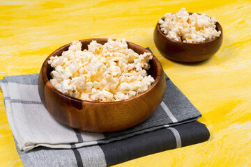 salted popcorn in bowl on yellow background. Top view with copy space. flat lay