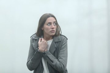Scared woman walking alone in a foggy park