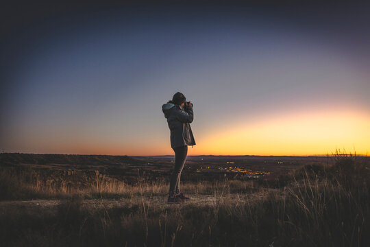Young girl taking pictures at night in the sunset on the mountain