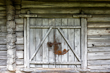 An old door with a rusty padlock in a wooden log house. Gray rustic background
