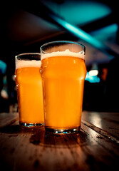 two glass of light beer stands on a table in a bar or pub