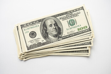 A money pile of stacked one hundred US banknotes with president Franklin portrait on white background. Cash of hundred dollar bills, paper money currency.