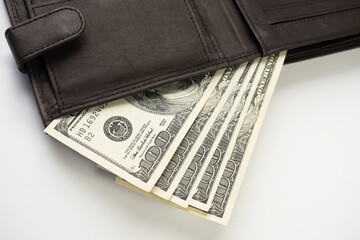 Leather wallet full of money on white background - fan of one hundred US banknotes with president Franklin portrait. Cash of hundred dollar bills, paper currency.