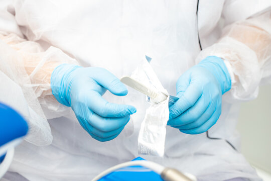 the dentist opens a disposable sterile scalpel during the implantation surgery