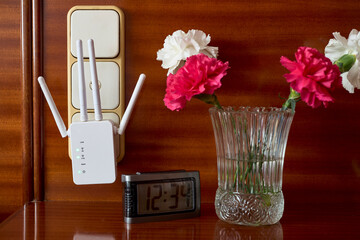 Router for Internet connection, vase of flowers and an alarm clock 