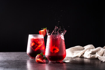 Strawberry cocktail splashing in a glass on black background
