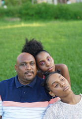 Family Portrait of Father and Daughters relaxing on Grassy Backyard