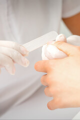 Close up of the hand of young woman receiving the nail file procedure in a beauty salon