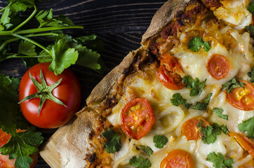 Pinsa with a decor in the form of tomatoes and greens on a colored background close-up. Pinsa home cooking.	