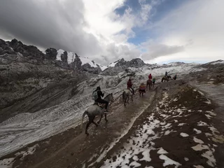 Fototapete Vinicunca Gruppe von Touristen reiten in verschneiter Winterlandschaft auf dem Weg zum Regenbogenberg Vinicunca in der Nähe der Anden von Cusco Peru