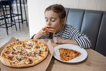 The little girl appetizingly eats a slice of pizza.