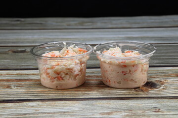 Traditional coleslaw, sliced cabbage and carrot mixed with salad cream serving in the plastic bowl. 