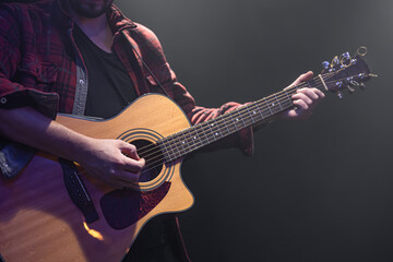 Acoustic guitar in the hands of a guitarist.
