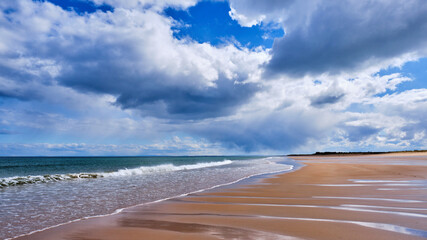 Brora beach on a sunny day with gentle waves breaking on the shore
