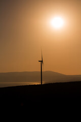 View of wind turbine, Aegean sea and landscpae at sunset captured in Sigacik / Seferihisar district of Izmir / Turkey. Wind power turbines for clean, renewable energy. Sustainability concept.