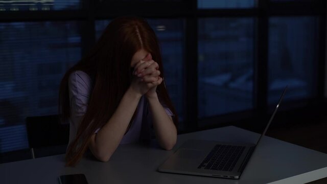 Close-up face of depressed lonely young woman folding palms together pray ask for help, feel stressed looks desperate by life problems. Sad female praying for his love sitting near window at night.