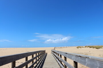 Long  Wooden bridge leading to the sandy beach and the Atlantic Ocean. Portugal beaches.