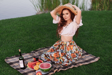 Obraz premium Beautiful young woman having picnic on sunny spring day in park.Pretty woman in park outside at sunny day, enjoying summertime and dreaming