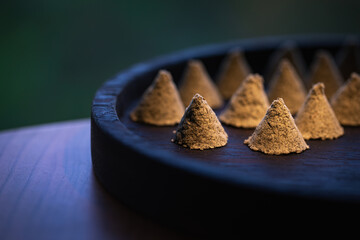 The conical moxa used for treatment is placed in a wooden dish. Moxa close-up. Moxa creative photography.