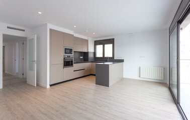 Barcelona, Spain. 9-25-2019. An empty brown kitchen of a brand new apartment with a big window sold...