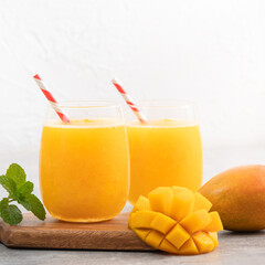 Fresh beautiful delicious mango juice smoothie in a glass cup on gray table background.