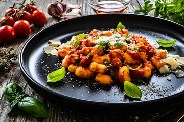 Gnocchi with in tomato sauce, parmesan and basil on wooden table

