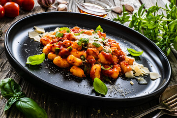 Gnocchi with in tomato sauce, parmesan and basil on wooden table
