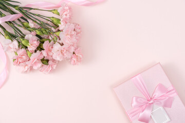 Mother's day background. Top view of gift with carnation bouquet on pink table background