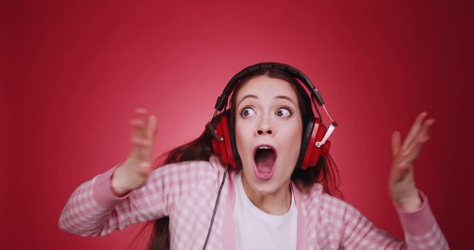Happy fun charismatic young brunette woman puts on big red headphones and dancing isolated on yellow studio background. Listening mind blowing groovy ecstatic uplifting dance music with pleasure