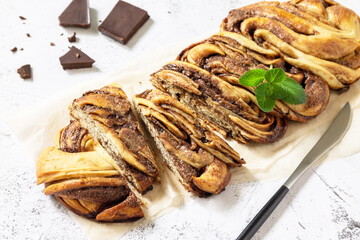 Fresh pastries, chocolate day. Chocolate babka or brioche bread. Sweet yeast dough with chocolate filling and accompanied and nuts.