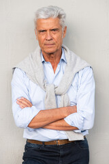 Front of handsome older man with arms crossed by white wall