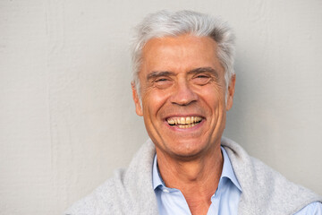 Fototapeta na wymiar Close up smiling older man against white wall
