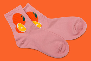 pair of pink socks with orange pattern lying on orange background