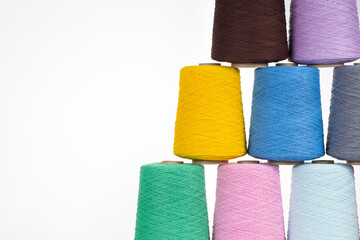 Spools of multicolored cotton thread on a white background lined up in a pyramid with space for text