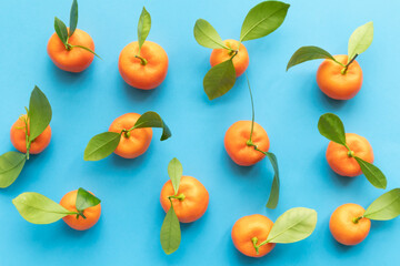 Clementines with leaves on a blue background. Top view with copy space.