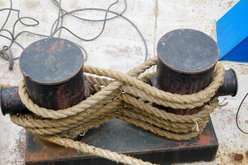 Fototapeta na wymiar Hemp rope with which the ship is tied at the stop. Cleat hitch concept for secure anchoring of mooring lines.