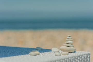 Fototapeta na wymiar white oval smooth stones lie on top of each other in the form of a pyramid on a sunbed on the beach in clear weather
