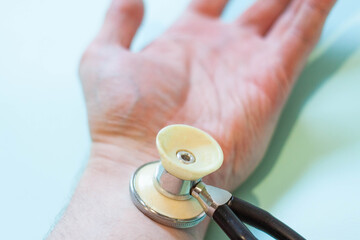 A man measures his own pressure with a stethoscope on his hand