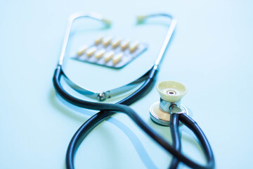 Stethoscope with medical medicine in capsules on blue background in hospital