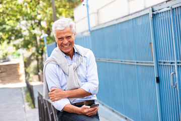 smiling man holding mobile phone outside