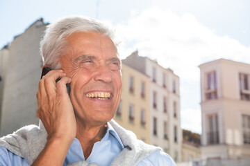 Close up happy older man talking with phone in city