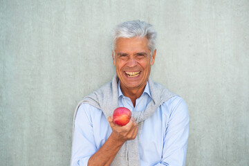 portrait older man smiling with apple by green background